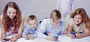 Ð¡asual Ñhildren using digital devices while sitting on the flo